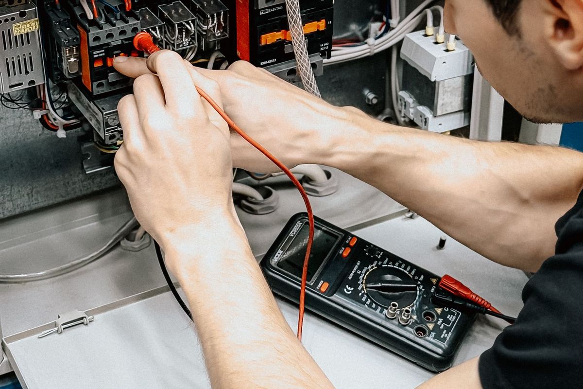 Elektryk sprawdza miernikiem połączenia w otwartej rozdzielnicy