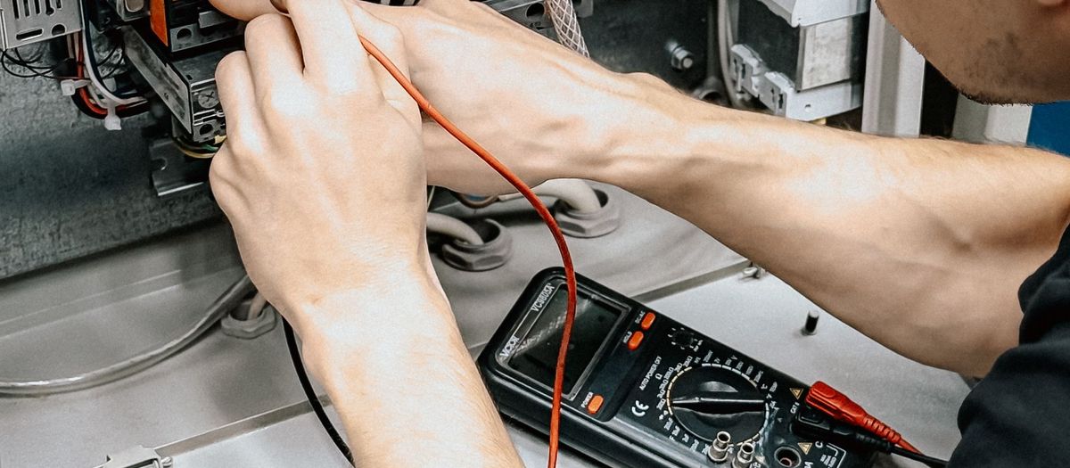 Elektryk sprawdza miernikiem połączenia w otwartej rozdzielnicy